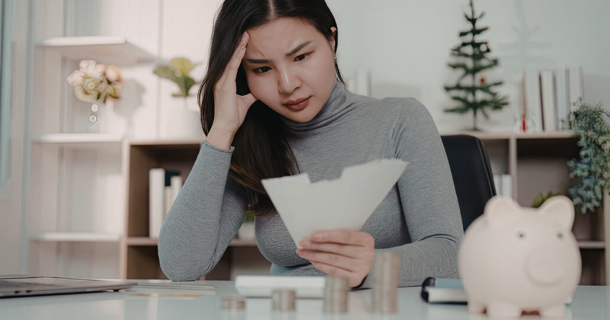 書類を見て不安そうな表情の女性と貯金箱